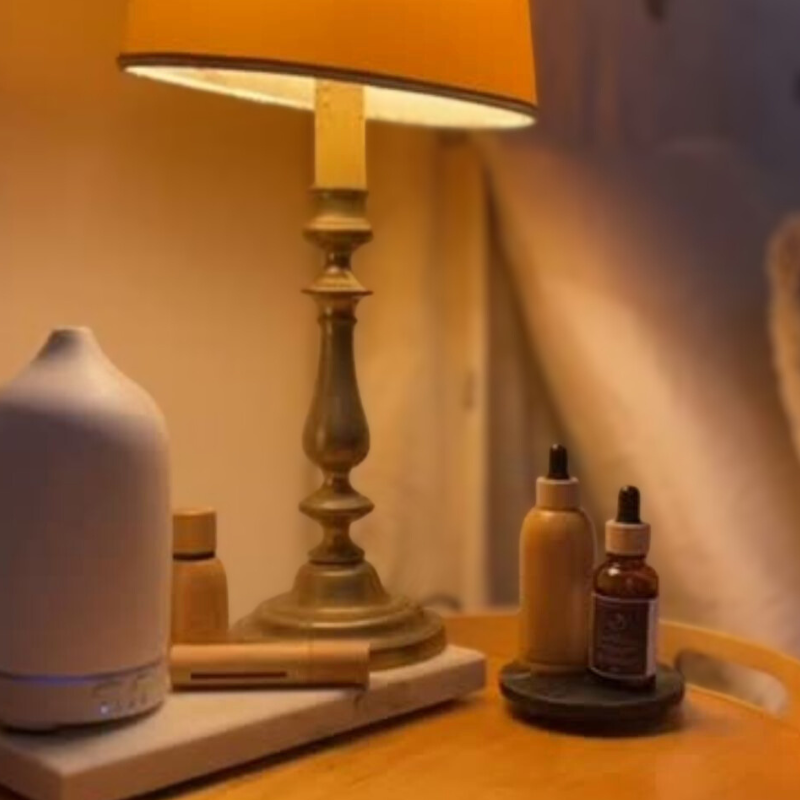 Sleep Boss sleep ritual on a bedside table in warm evening light: ceramic diffuser, essential oil roller and sleep luxury oil