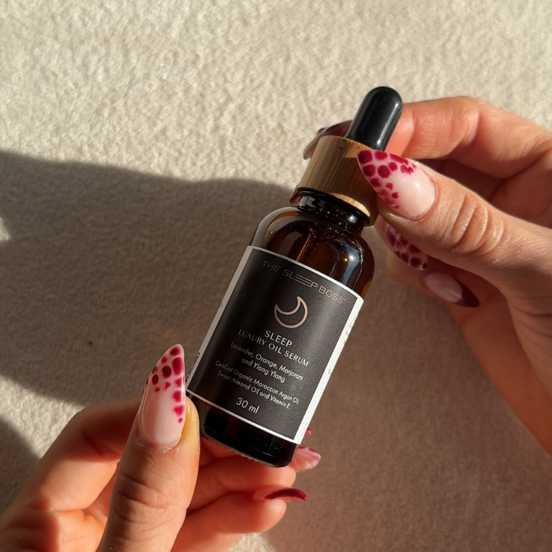 Hand holding a dropper bottle labeled 'Sleep' against a neutral background