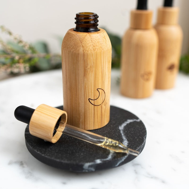 Sleep Luxury Oil serum blend in bamboo casing on top of a black marble stone