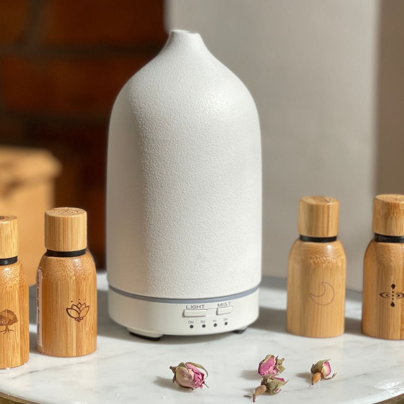 white ceramic aroma diffuser and oil essentials beside it